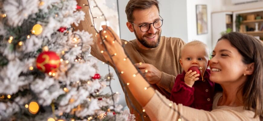 Young,Parents,Having,Fun,Decorating,Christmas,Tree,With,Their,Cute